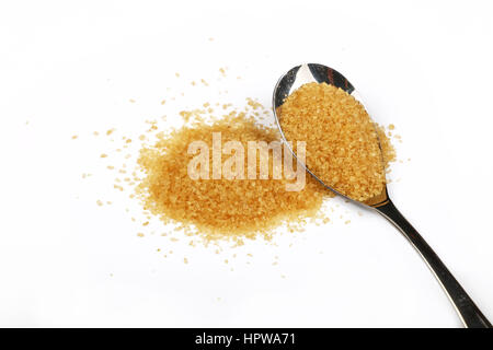 Cuillère en métal plein de sucre de canne brun avec pincée de sucre renversé autour d'isolé sur fond blanc, Close up, high angle view Banque D'Images