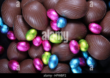 Pile de papier aluminium enveloppé & unwrapped chocolate Easter eggs en rose, bleu et vert anis. Banque D'Images