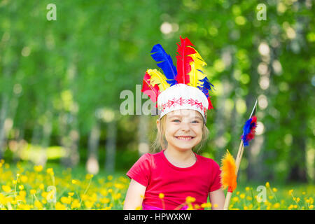 Peu drôle fille jouant native american dans parc d'été Banque D'Images