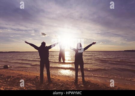 Famille heureuse avec un bébé au coucher du soleil nous tenir la main Banque D'Images