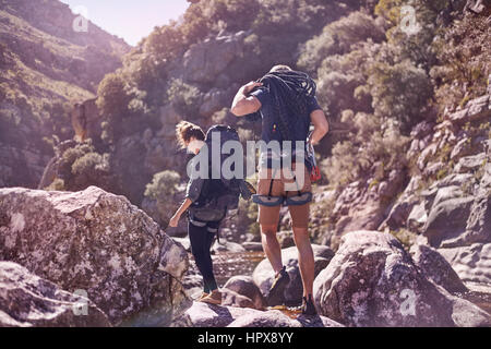 Jeune couple avec sacs à dos randonnée sur les rochers ensoleillés Banque D'Images