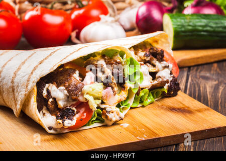 Sandwich roulé frais savoureux avec du boeuf, légumes et sauce tzatziki Banque D'Images