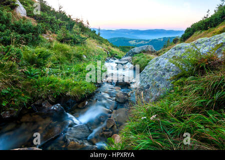 Belle petite cascade dans les montagnes avec de l'eau blanc soyeux mousseuse Banque D'Images