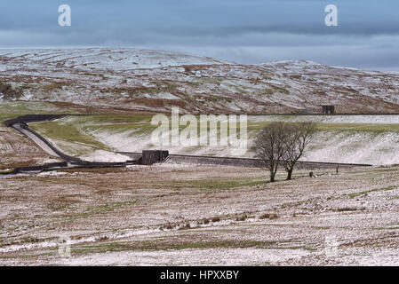 Débordement Reservior Largs avec station de pompage de l'époque victorienne et s'enfuir avec la neige sur les collines. Prises sur une journée froide. Deux arbres au centre de l'image. Banque D'Images