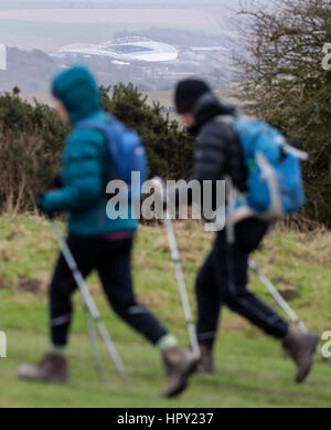 L'AMEX Stadium est vu dans l'arrière-plan comme deux randonneurs font leur chemin le long de la South Downs Way près de l'avant le ciel Ditchling Beacon parier Championship match au stade AMEX, Brighton. Banque D'Images