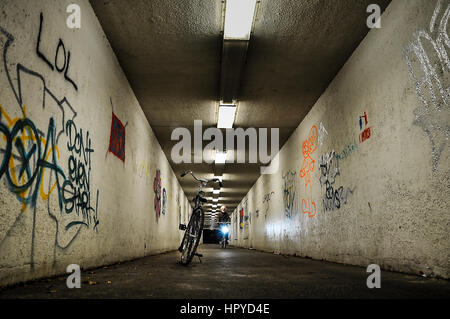 Garage à vélo dans un tunnel et un homme qui passe la bicyclette passant Banque D'Images