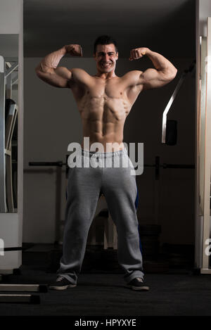 Portrait d'un jeune homme en montrant le double avant Pose Biceps musclé Bodybuilder - Athletic Fitness Model Posing Banque D'Images