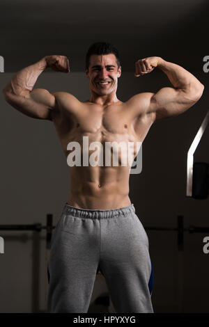 Portrait d'un jeune homme en montrant le double avant Pose Biceps musclé Bodybuilder - Athletic Fitness Model Posing Banque D'Images