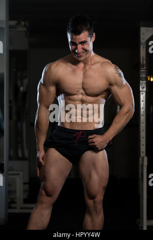 Portrait d'un jeune homme en bonne forme physique montrant son corps bien formé - Athletic musculaire Fitness Model Posing Bodybuilder Exercices après Banque D'Images