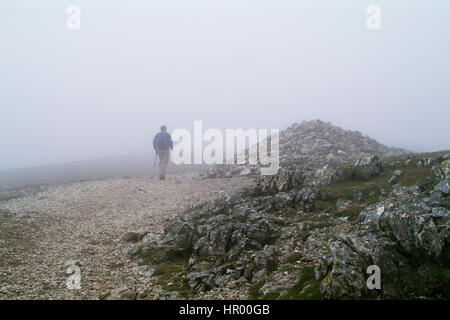 Lone walker dans le brouillard sur le chemin de l'établissement Stony Mountain par grand cairn près de Scafell Pike dans le lake district Banque D'Images