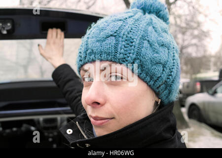 Jeune femme sur le point d'ouvrir ou fermer le coffre d'une voiture, concept de voyager en voiture. Portrait en extérieur portrait Banque D'Images