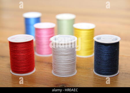 Coton de couleur multi-bobines ou bobines sur une table à couture en bois Banque D'Images