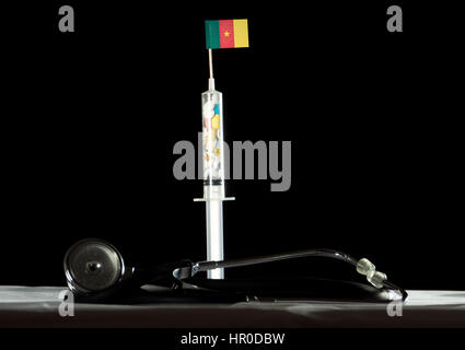 Stéthoscope et seringue remplie de l'injection de drogues le drapeau camerounais sur fond noir Banque D'Images