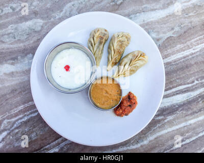 Libre et selective focus du Népal Momos, raviolis cuits à la vapeur traditionnelle ou momos avec une sauce tomate et du yaourt Banque D'Images