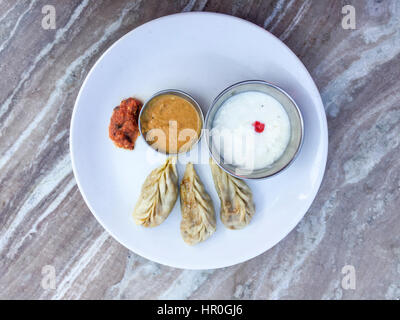 Libre et selective focus du Népal Momos, raviolis cuits à la vapeur traditionnelle ou momos avec une sauce tomate et du yaourt Banque D'Images