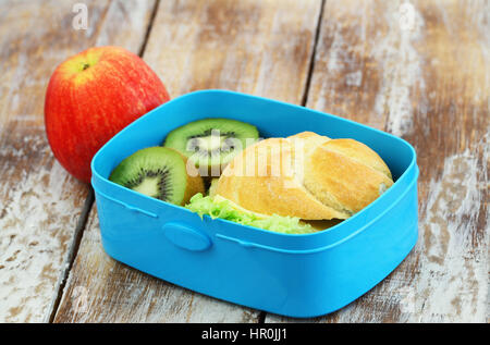 School lunch box sandwich au fromage contenant des fruits : kiwi et pomme sur la surface en bois rustique Banque D'Images