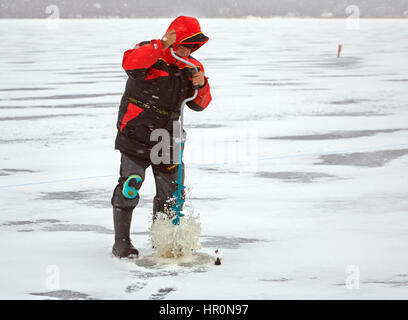 Riga, Lettonie. Feb 25, 2017. Un pêcheur perce un trou dans un lac gelé près de Riga, Lettonie, 25 février 2017. Les deux jours de compétitions pour le championnat du monde à la pêche sur glace a commencé en Lettonie le samedi. Photo : Alexander Welscher/dpa/Alamy Live News Banque D'Images