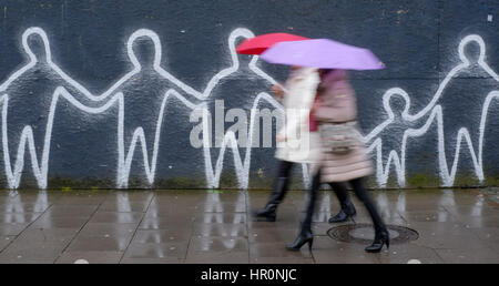 Hambourg, Allemagne. Feb 25, 2017. Les piétons marchent dans la pluie battante passé un mur de graffiti sur place Spielbudenplatz à Hambourg, Allemagne, 25 février 2017. Photo : Axel Heimken/dpa/Alamy Live News Banque D'Images