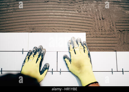 Carreleur, holding industriel et l'installation de carreaux de salle de bain en céramique au cours de travaux de rénovation Banque D'Images