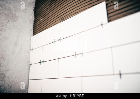 Rénovation des salles de bains, Close up détails de distancer en plastique sur les carreaux en céramique et de l'adhésif sur les murs Banque D'Images