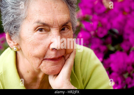 Belle senior woman portrait en face de fleurs violettes Banque D'Images