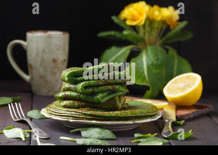 Crêpes aux épinards sur table en bois et jaune primevère. Banque D'Images