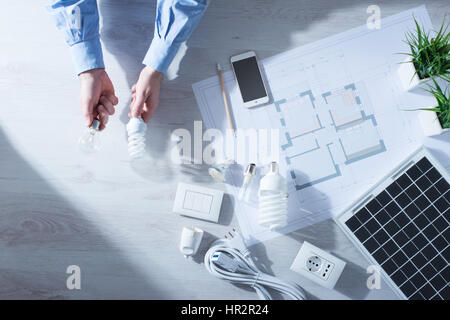 La comparaison d'un homme et d'une ampoule à incandescence obsolètes CFL ampoule à économie d'énergie, projet maison et panneau solaire Banque D'Images