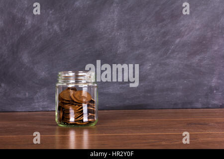 Pot de verre sur une surface en bois remplie de vieilles pièces Banque D'Images