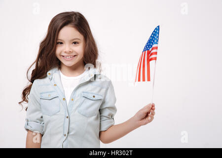 Fier d'être le citoyen de ce pays. Heureux joyeux cheerful girl holding le drapeau américain tout en exprimant la positivité et isolés dans Banque D'Images