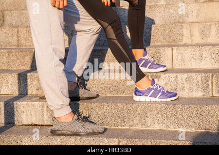 L'exécution libre. Libre de chaussures de course et Girl standing avec petit ami pendant la formation d'entraînement jogging en plein air sur des mesures pour se détendre. Banque D'Images