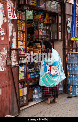 Marrakech, Maroc. Woman shopping au magasin d'articles divers, El-Kedim Zeitoun Street. Banque D'Images