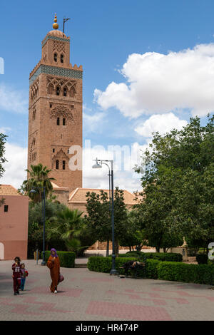 Marrakech, Maroc. Mère et filles avec de la crème glacée, Koutoubia, 12e. Siècle, en arrière-plan. Banque D'Images