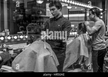 Deux jeunes hommes ayant leur coupe de cheveux, dans un vieux salon de coiffure à la mode du marché des Spitalfields, Londres, Angleterre, Royaume-Uni Banque D'Images