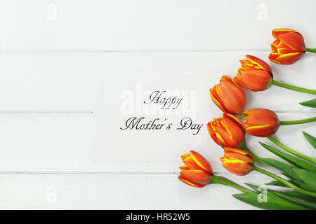 Passage tiré d'un bouquet d'orange et jaune printemps tulipe fleurs et Happy Mother's Day card sur table en bois blanc dessus. Télévision jeter dessus style. Banque D'Images