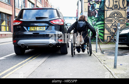 Utilisateur de fauteuil roulant a du mal à passer par mal voiture en stationnement sur la chaussée et double lignes jaunes à Brighton, UK Banque D'Images