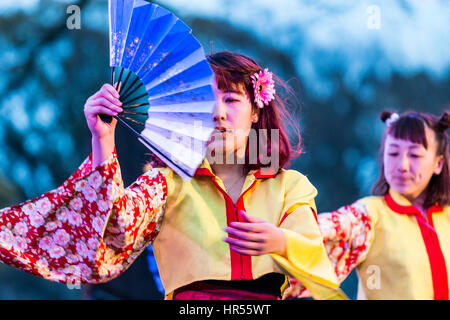 Danse Yosakoi Festival. Deux jeunes danseurs en yukata femme jaune vestes et manches longues, holding open fans en dansant sur scène. En soirée. Close up. Banque D'Images