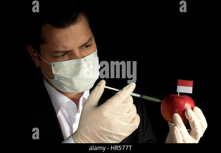 Jeune homme d'injection de produits chimiques dans un apple avec Monaco drapeau sur fond noir Banque D'Images