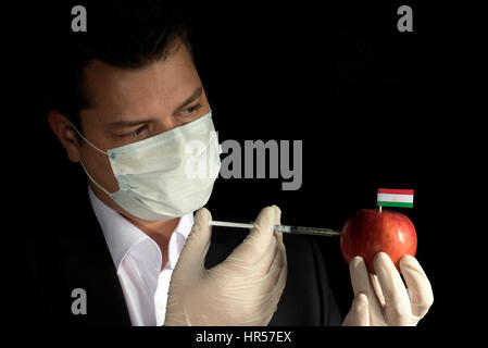 Jeune homme d'injection de produits chimiques dans un apple avec le Tadjikistan drapeau sur fond noir Banque D'Images