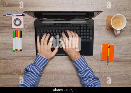 La main des hommes travaillant sur ordinateur portable dans son bureau alors qu'il boit du café Banque D'Images