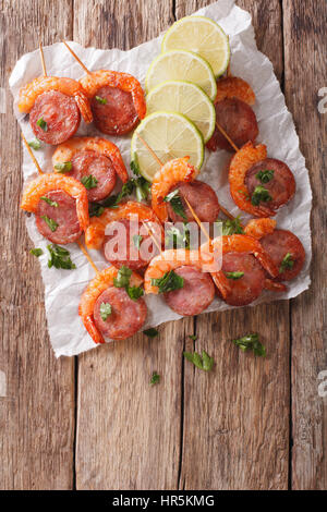 Gambas grillées avec du chorizo et des herbes sur les brochettes, close-up sur la table. vertical Vue de dessus Banque D'Images