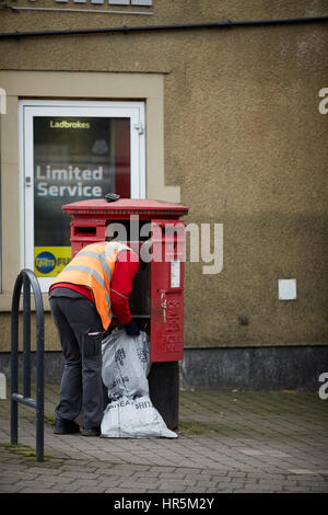 Postman en uniforme le vidage des lettres d'un rouge Royal Mail postbox à Hare Hill Road, Village Littleborough, Rochdale, Lancashire, England, UK. Banque D'Images