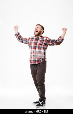 Image pleine longueur de Screaming heureux homme barbu en shirt standing in studio. Isolé sur fond blanc Banque D'Images