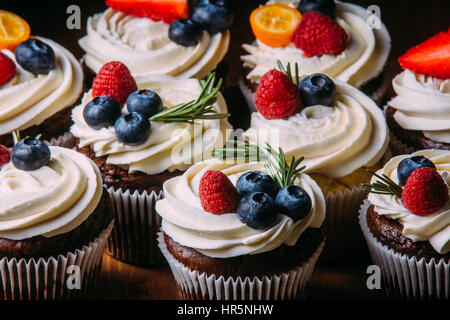 Petits gâteaux au chocolat savoureux frais aux fruits rouges. Focus sélectif. Fond en bois foncé.style rustique, place pour le texte. Banque D'Images