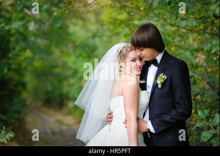 Groom hugs madame en promenade dans le parc d'été. Banque D'Images