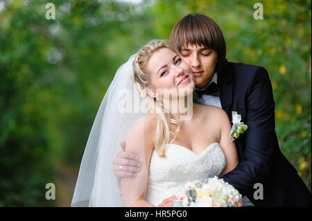 Groom hugs madame en promenade dans le parc d'été. Banque D'Images