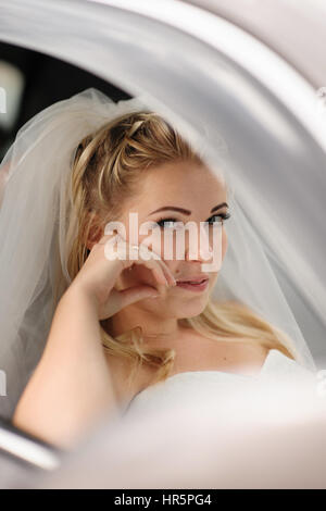 Happy bride sitting dans la voiture de mariage. Banque D'Images