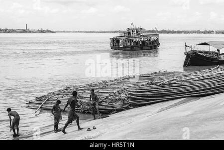 Les gens se baigner dans la rivière Hoogly comme un port pour le transport de passagers le long de la rivière en été que le bambou attend d'être chargés et transportés. Banque D'Images