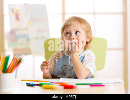 Smiling kid dessin avec des crayons de couleurs en garderie Banque D'Images