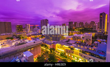 Crépuscule violet des rues de la région de Waikiki, dans l'île d'Oahu, Hawaii, United States. La vie nocturne de la ville de veilleuses et de concept. Banque D'Images