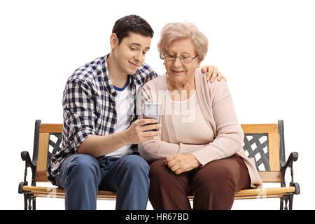 Jeune homme assis sur un banc avec une femme mature et lui montrant quelque chose sur un téléphone isolé sur fond blanc Banque D'Images